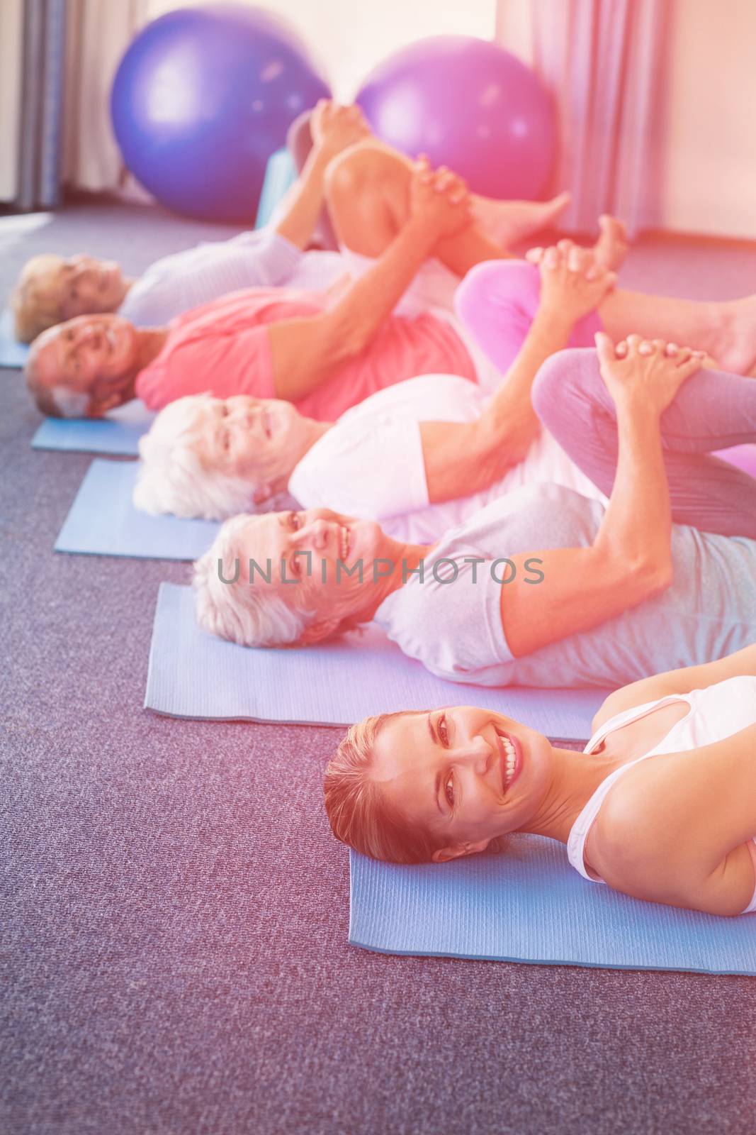 Portrait of instructor performing yoga with seniors during sports class