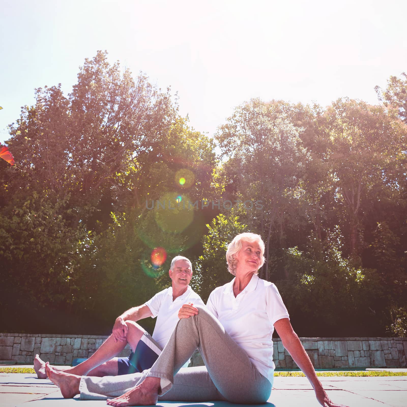 Senior couple exercising at poolside against sky during sunny day