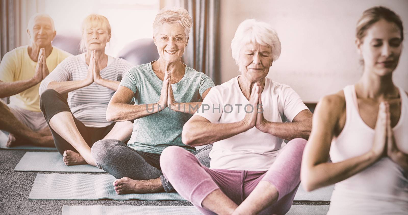 Instructor performing yoga with seniors during sports class