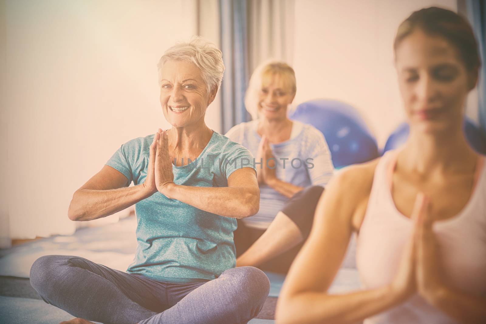 Instructor performing yoga with seniors during sports class