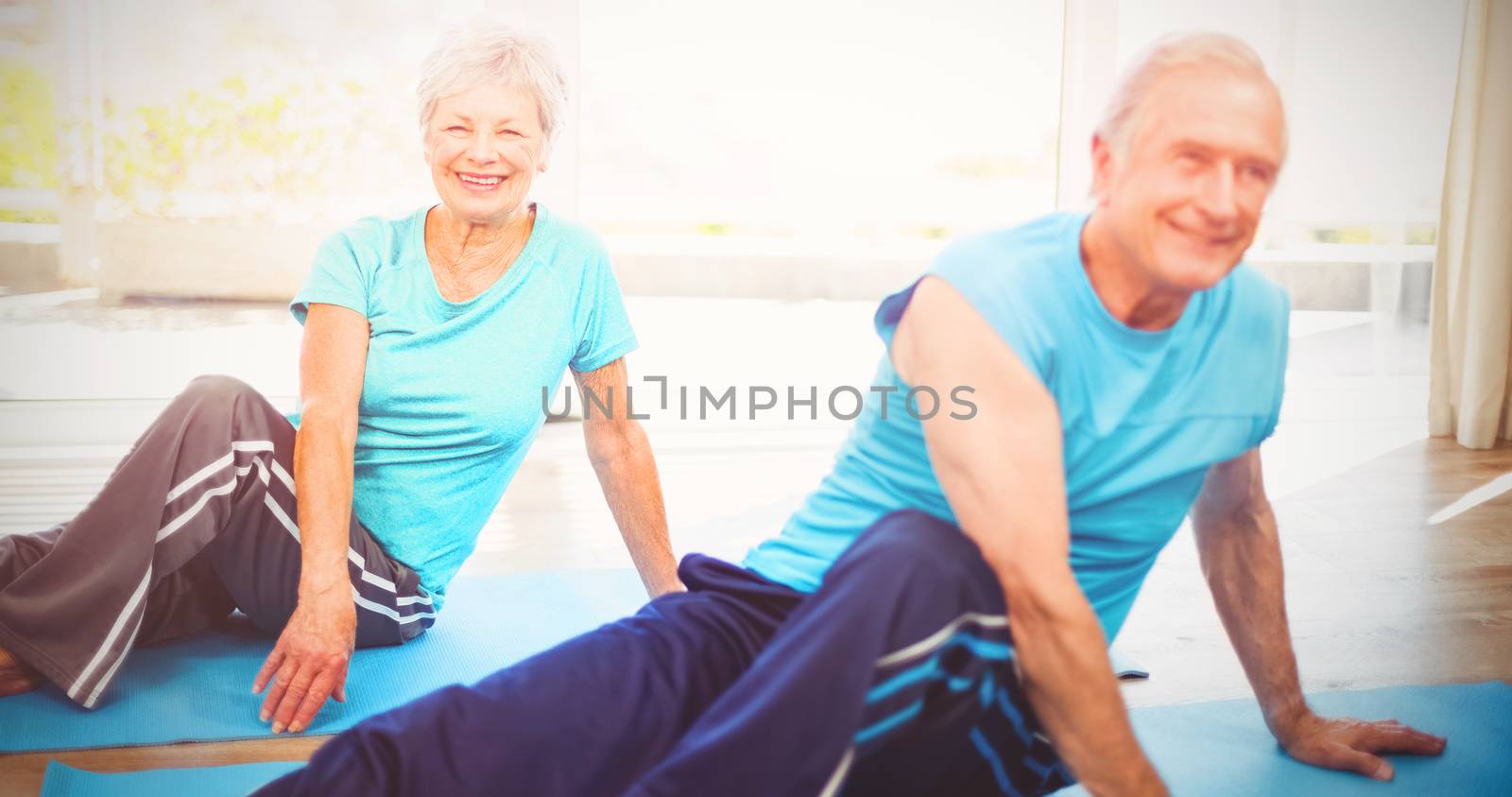 Happy senior couple doing yoga on exercise mat at home