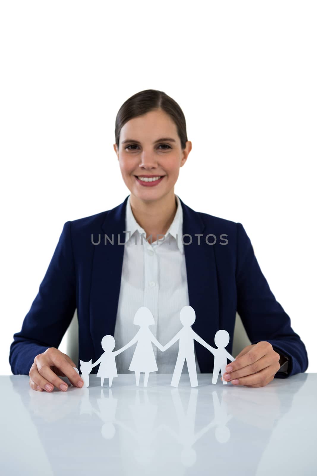 Portrait of smiling businesswoman holding paper cut out of family against white background