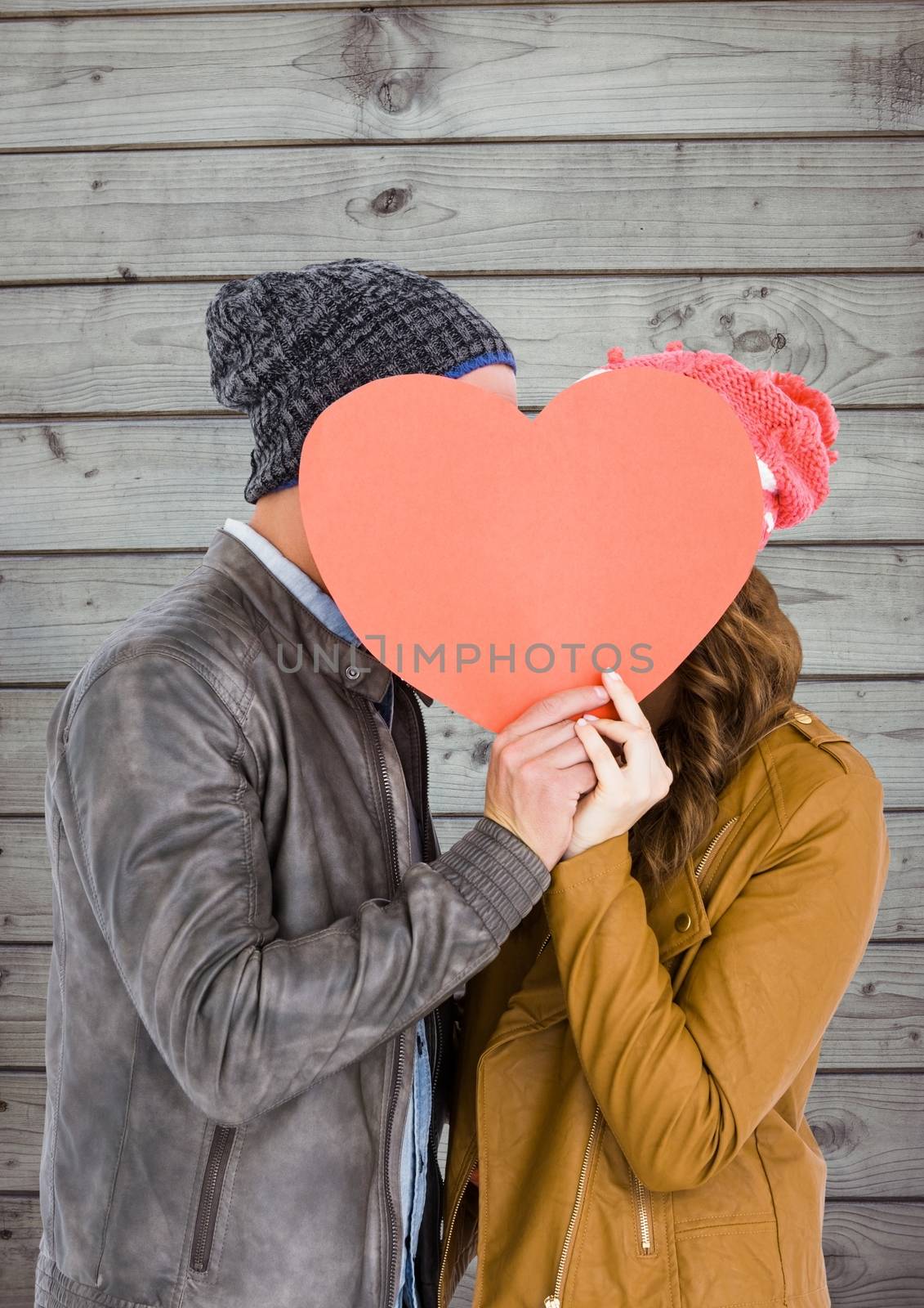 Romantic couple holding heart shape and kissing each other against wooden background