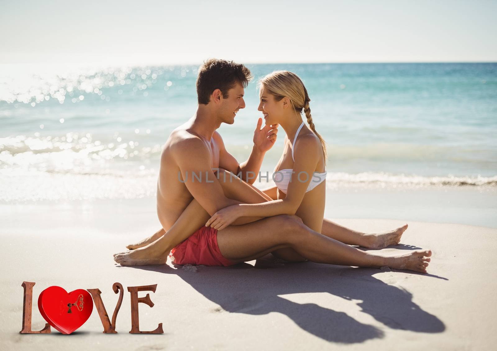 Composite of romantic couple sitting on beach with text love in foreground