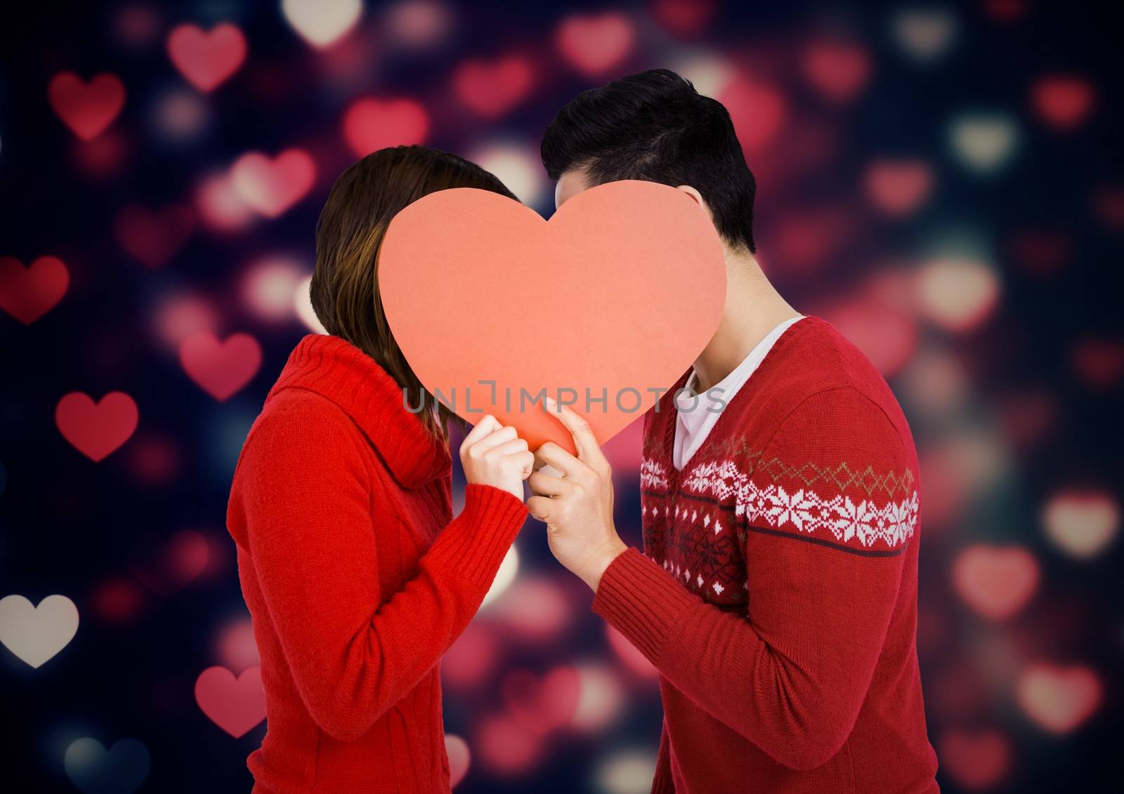 Romantic couple hiding their face behind heart against digitally generated background