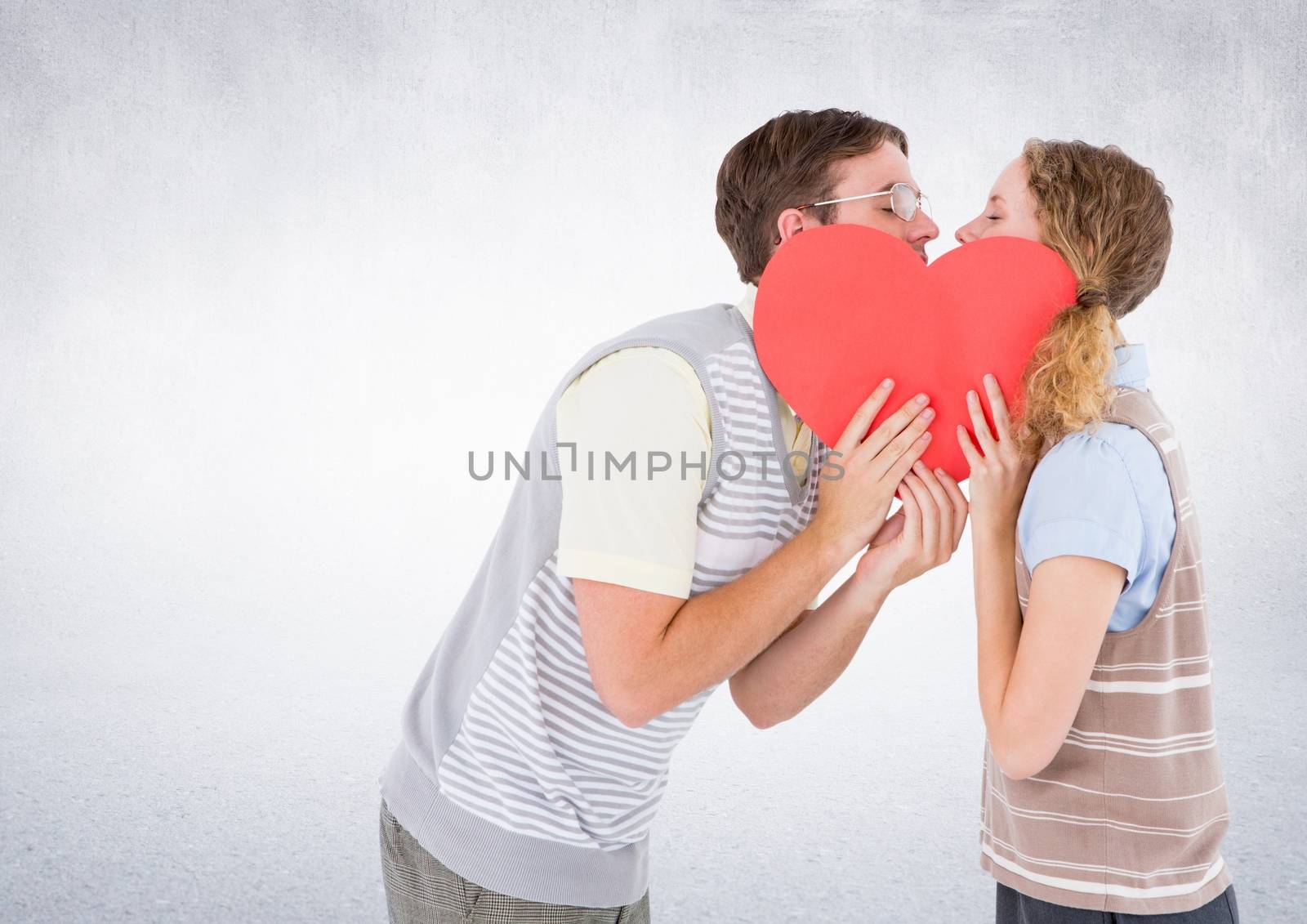 Romantic couple kissing behind heart against white background