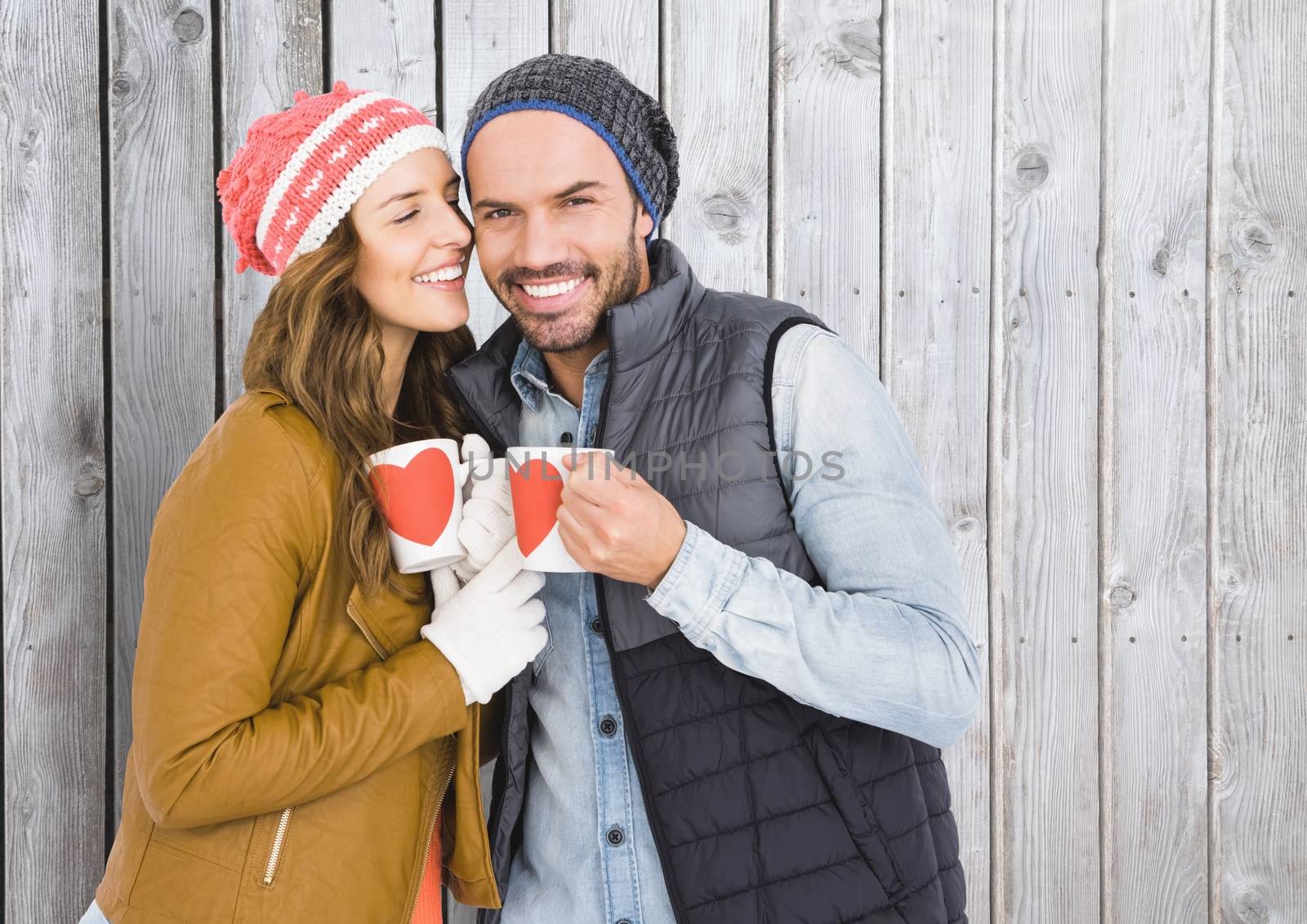 Romantic couple holding coffee mugs against wooden background