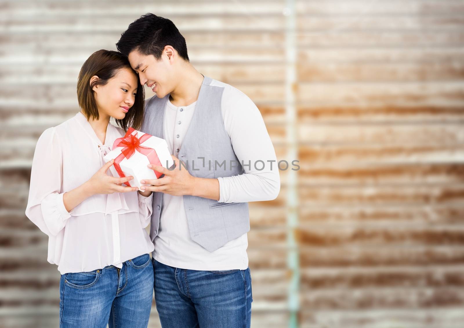 Romantic couple holding gift box against digital composite background