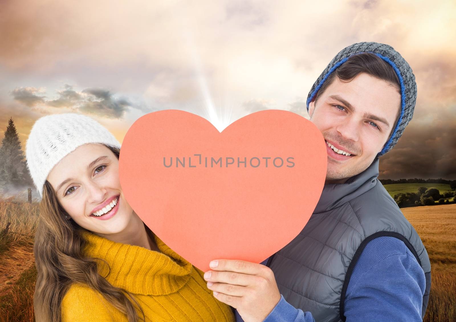Portrait of romantic couple holding heart against digitally composite field background