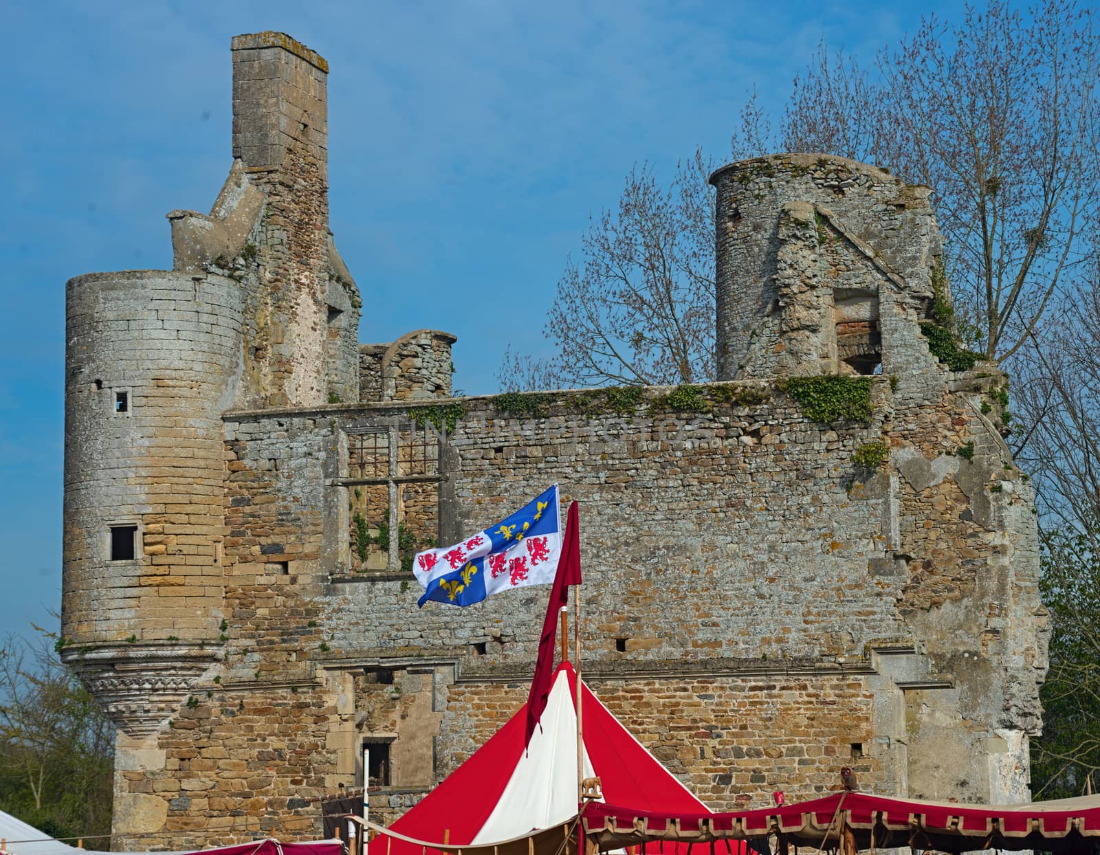 Top of medieval red and white tent with normandy flag at top and castle in background