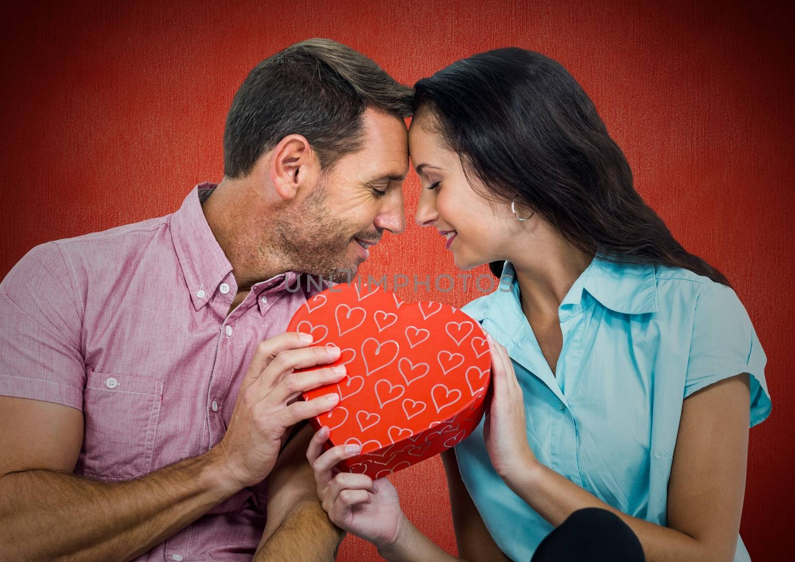 Romantic couple holding a gift box against red background