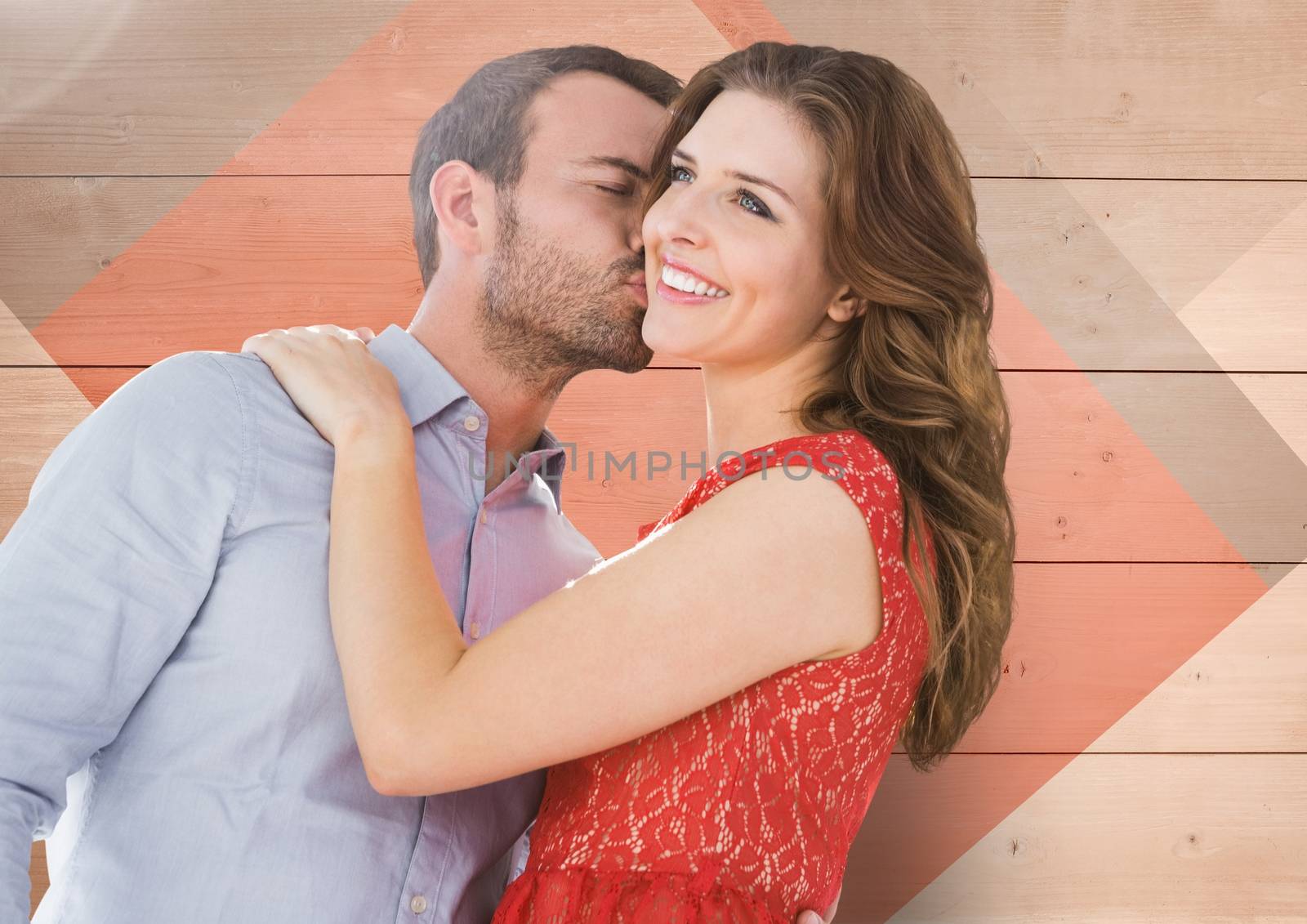 Romantic man kissing on woman cheeks against wooden background