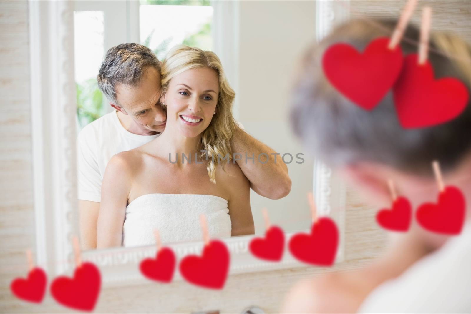 Composite image of romantic couple embracing in front of mirror with red hearts hanging on line