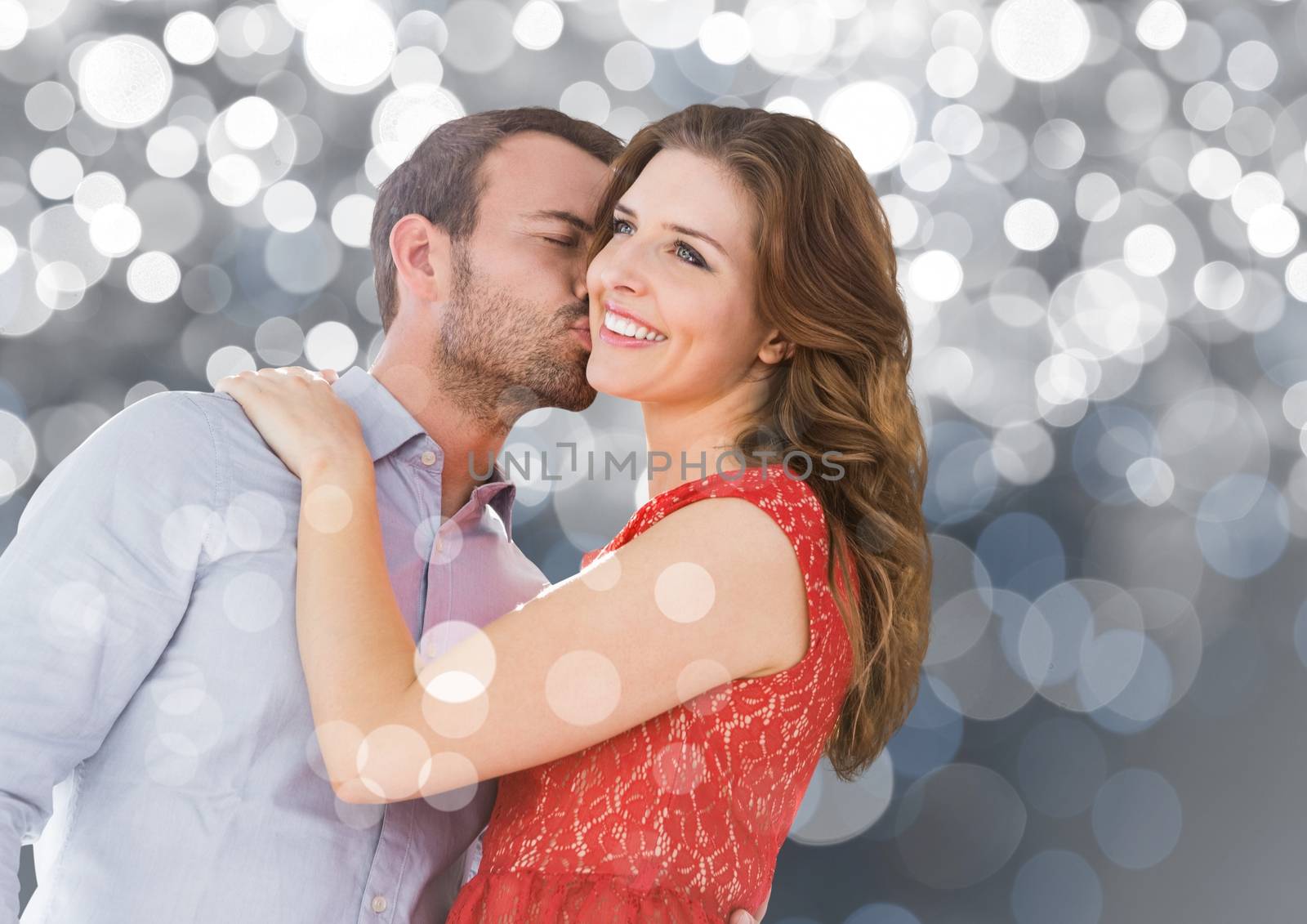 Romantic couple kissing against silver bokeh background