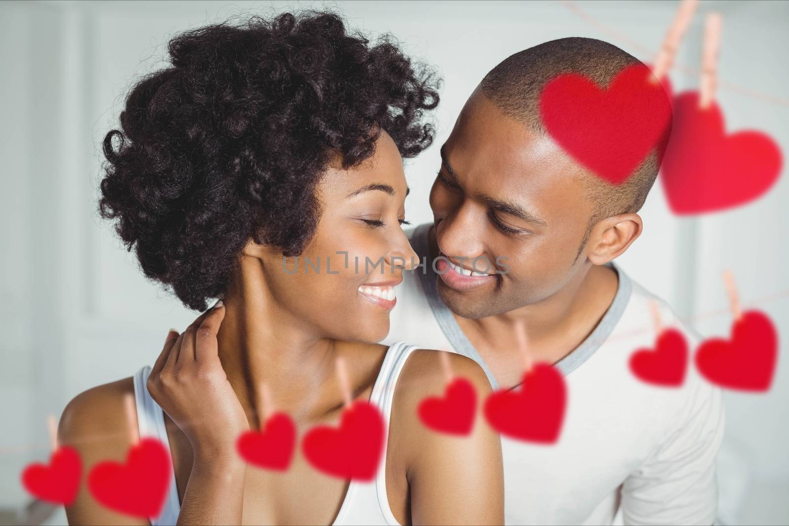 Composite image of romantic couple embracing each other with red hearts hanging on line