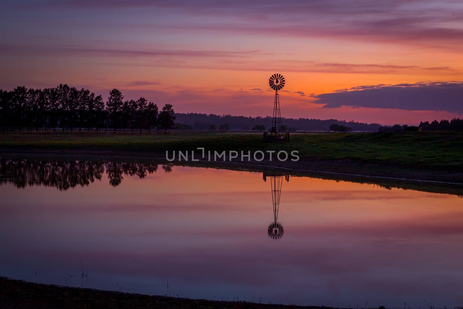 Sunrise over dam with wind mill in rural Australia by lovleah
