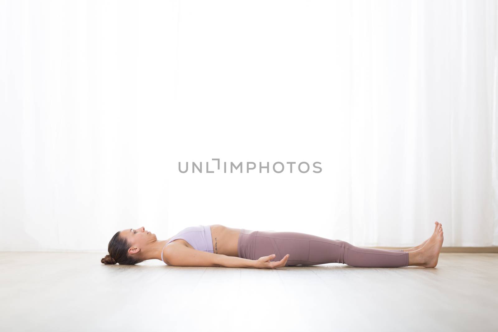 Portrait of gorgeous active sporty young woman practicing breathing exercises in yoga studio. Healthy active lifestyle, working out indoors in gym.