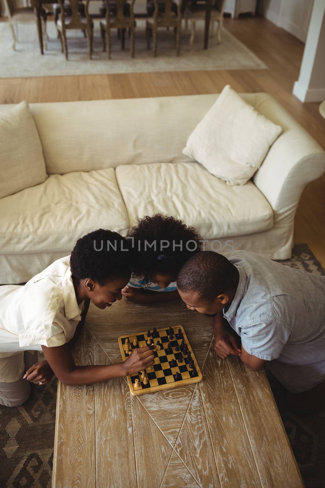 Family playing chess together at home in the living room by Wavebreakmedia