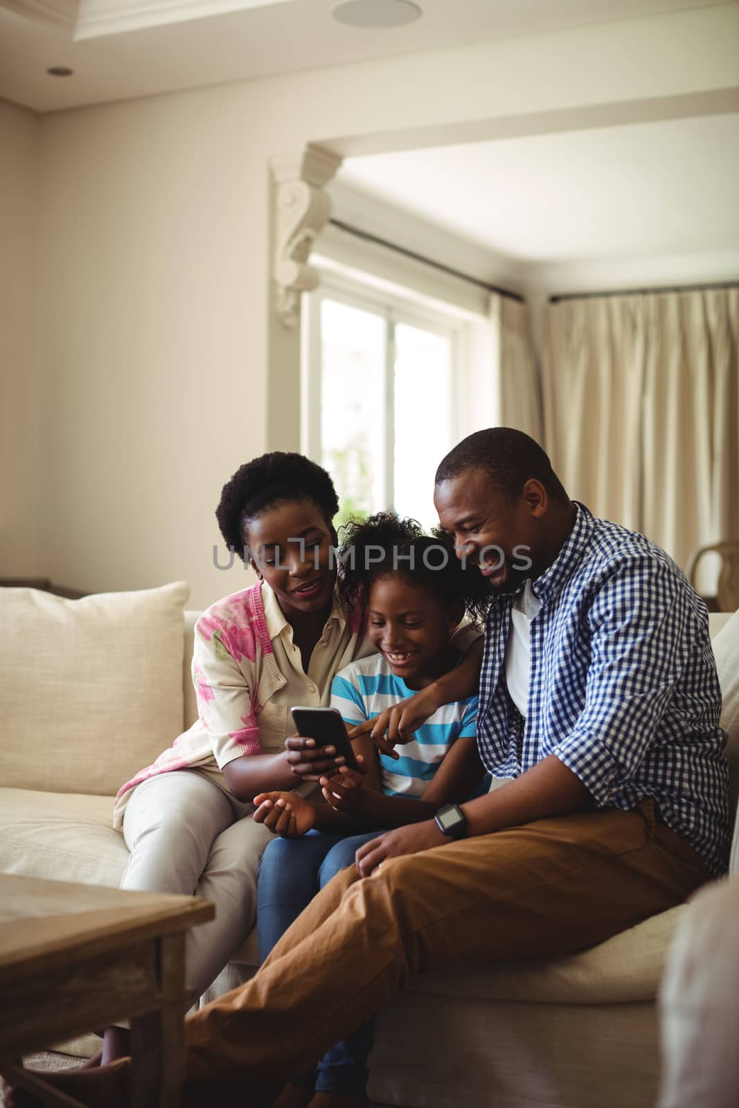Family using mobile phone in living room at home