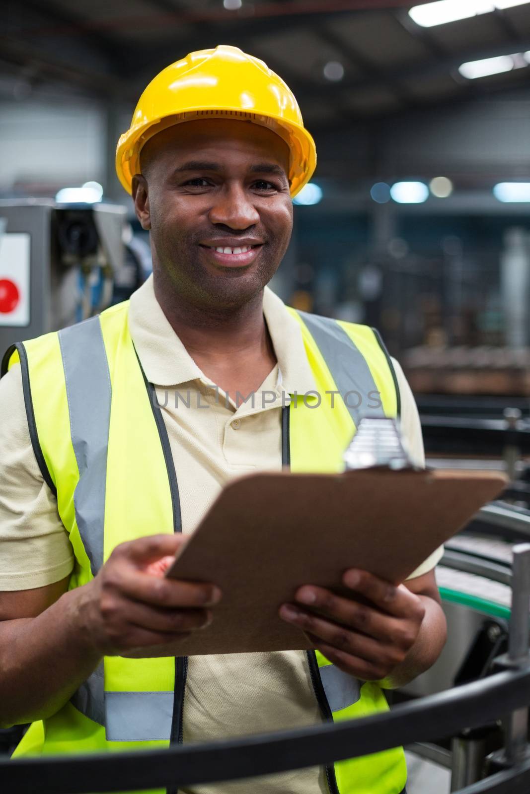 Smiling factory worker holding clipboard in factory by Wavebreakmedia