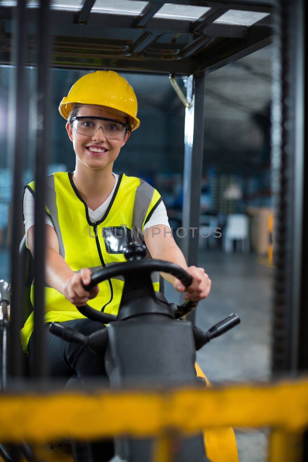Portrait of smiling female factory worker driving forklift by Wavebreakmedia