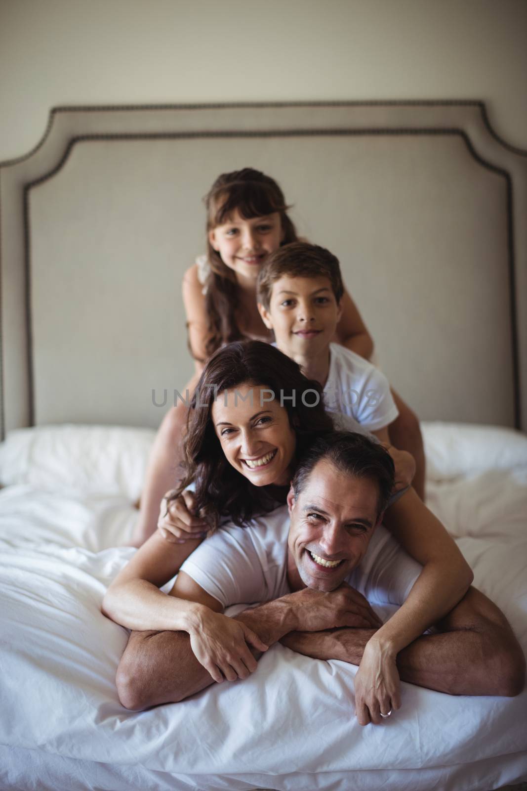 Happy family stacking on top of each other on the bed by Wavebreakmedia