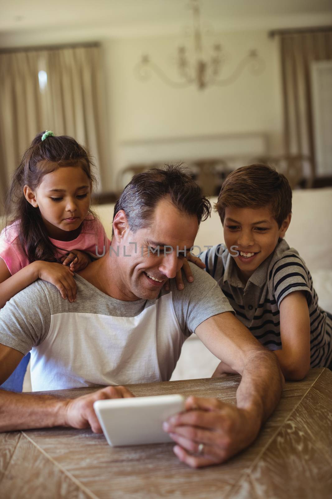 Father and kids using digital tablet in living room at home