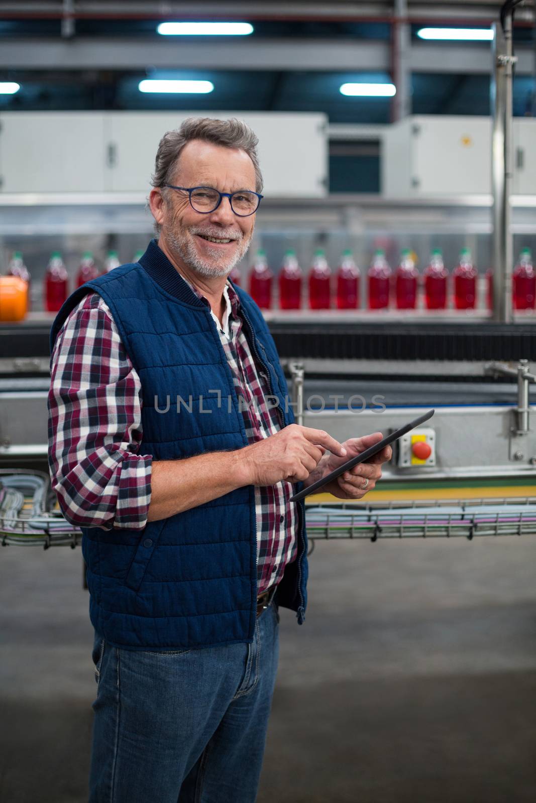 Smiling factory worker using digital tablet at drinks production plant by Wavebreakmedia