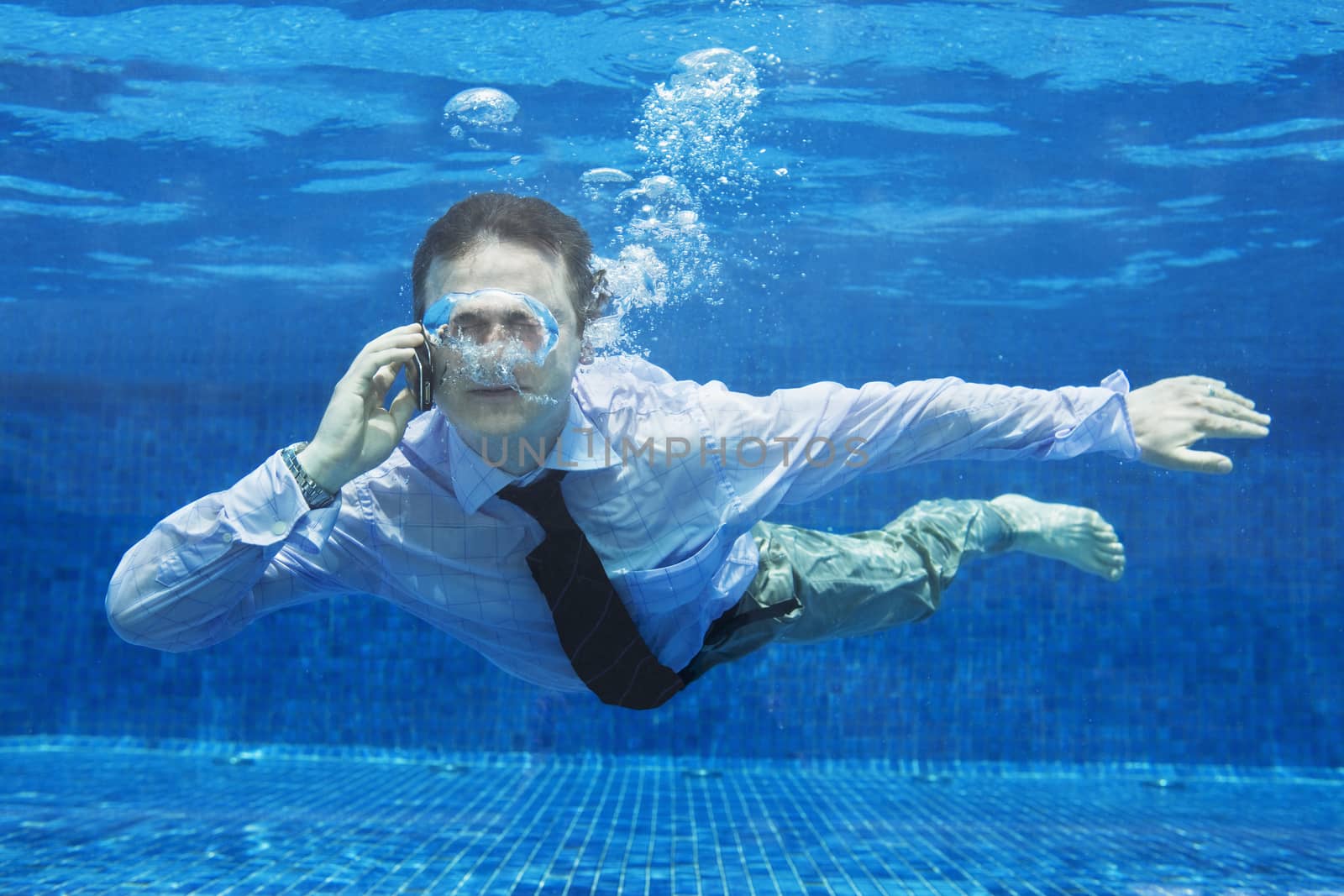 Caucasian businessman talking on a mobile phone underwater themes of danger helpless challenge