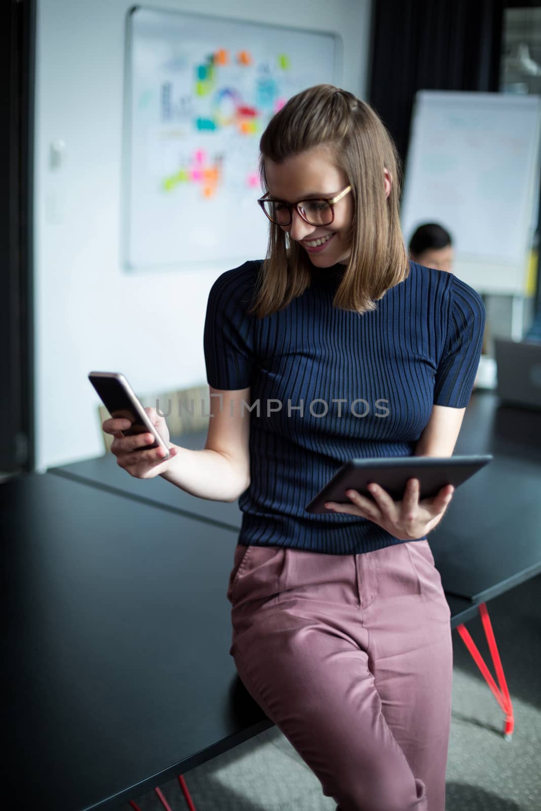 Business executive using mobile phone and digital tablet in office
