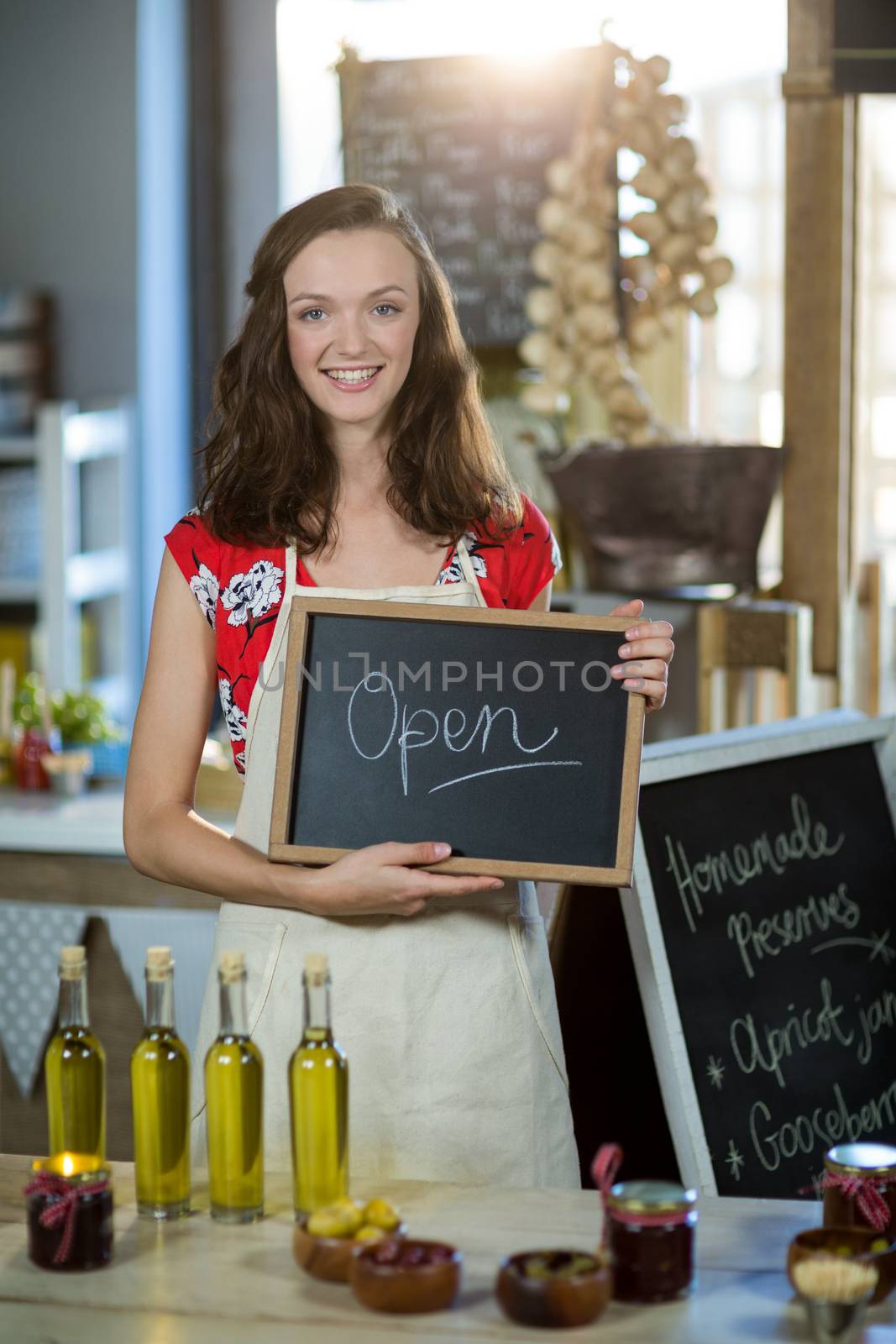 Female shop assistant holding open sign board by Wavebreakmedia