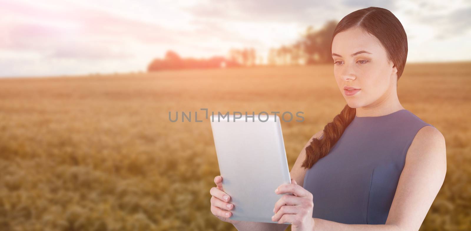 Beautiful woman using digital tablet against sky over golden fields