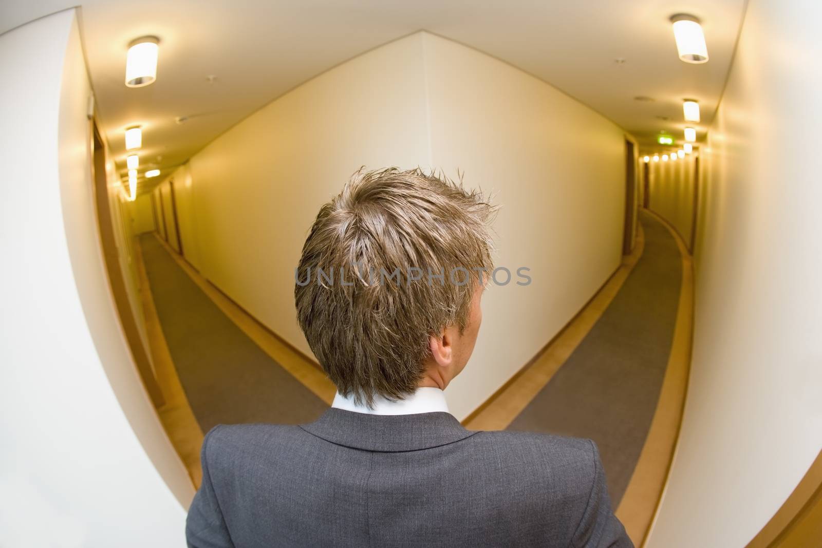 A businessman looking down the corridoor of a hotel themes of travel working late arrival choice