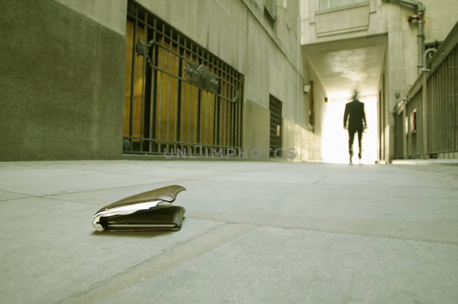 Low angle view of a businessman walking who has dropped his wallet themes of loss carelessness finance