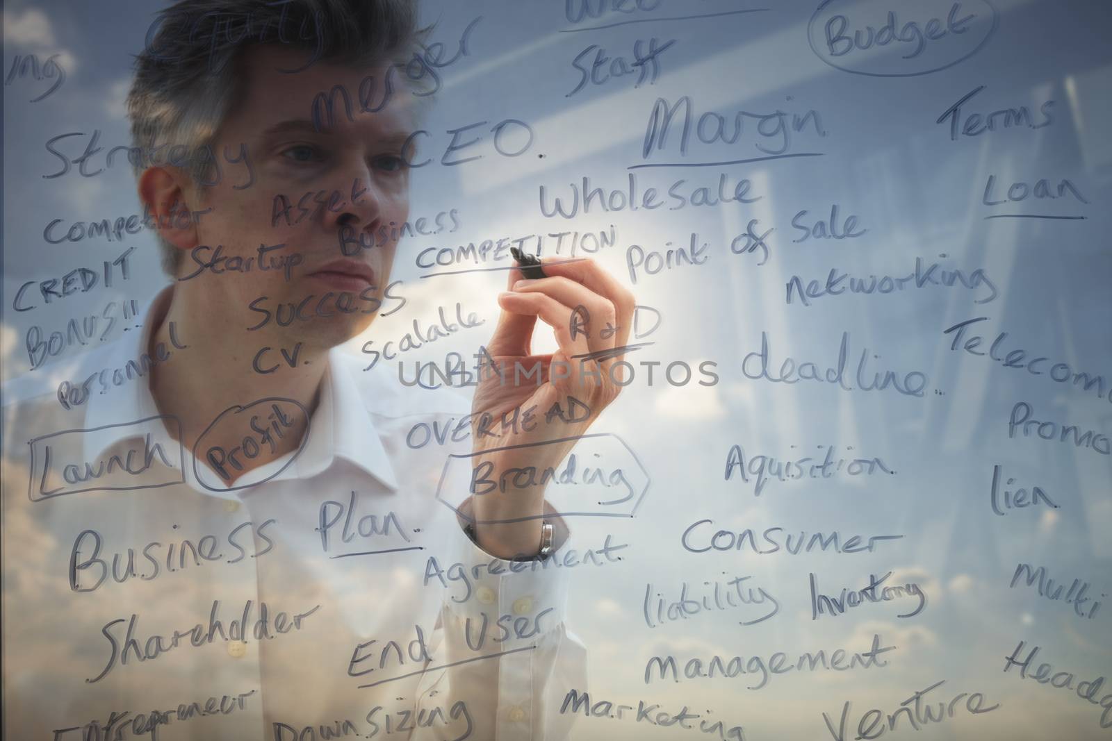 Reflection of a businessman brainstorming writing keywords onto glass