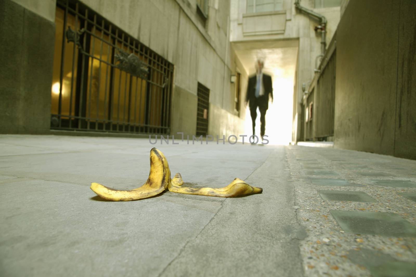 Low angle view of a businessman walking towards a banana skin themes of careless danger risk