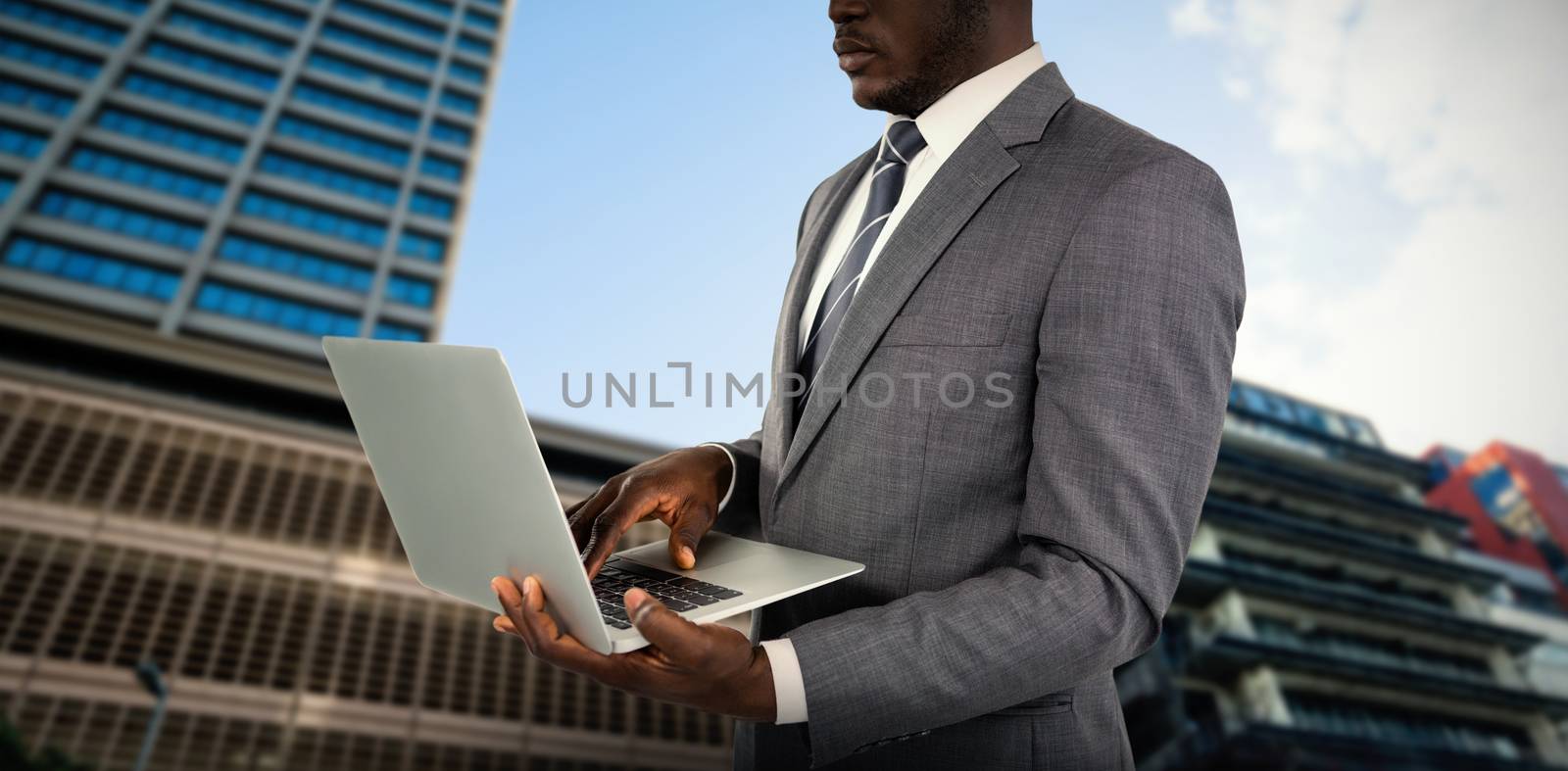 Midsection of businessman using laptop against building against cloudy sky