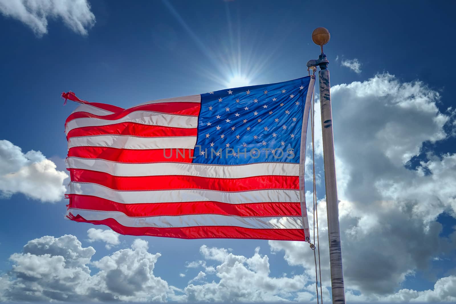 An American flag blowing in the wind and backlit from the sun