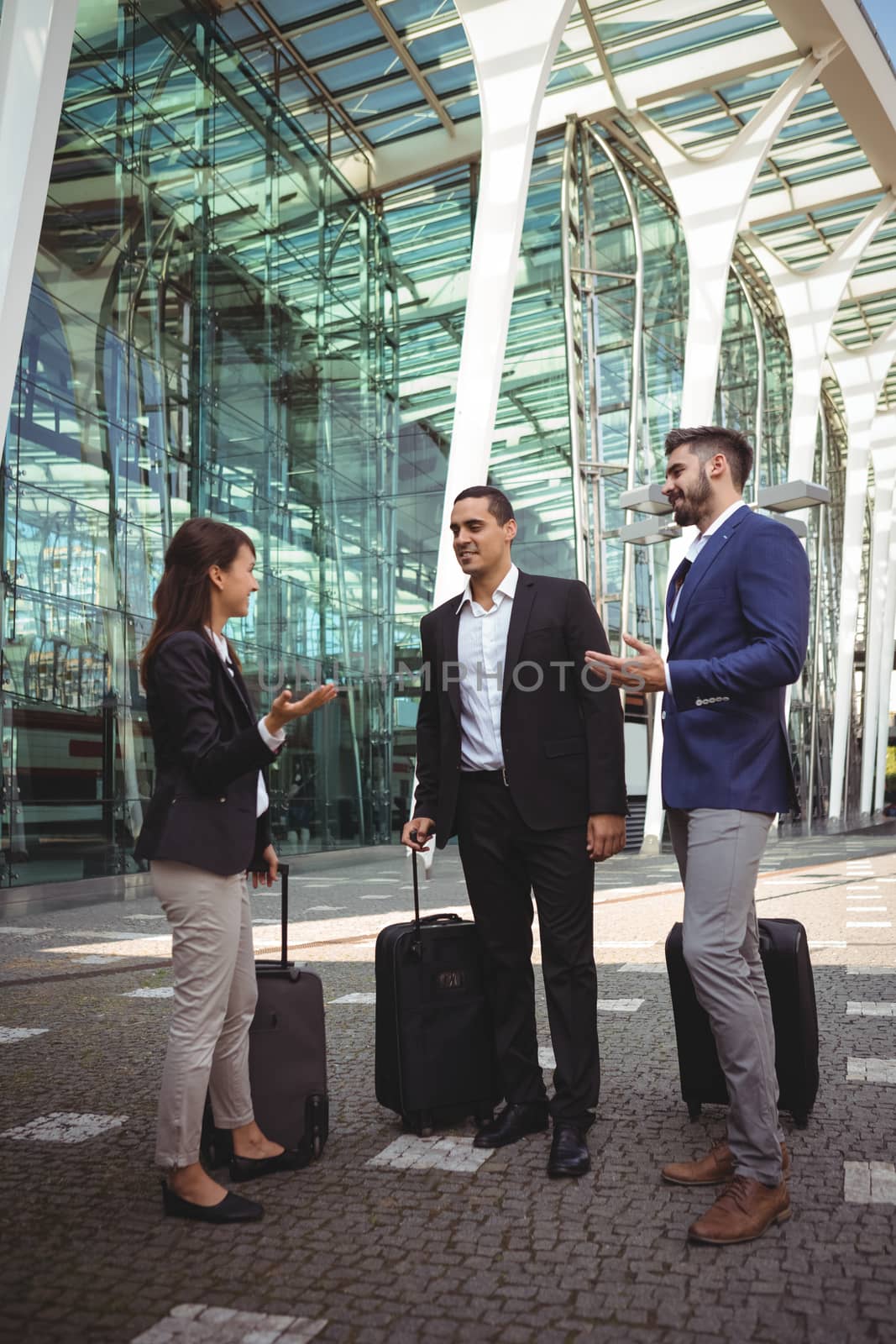 Smiling business executives interacting with each other outside platform