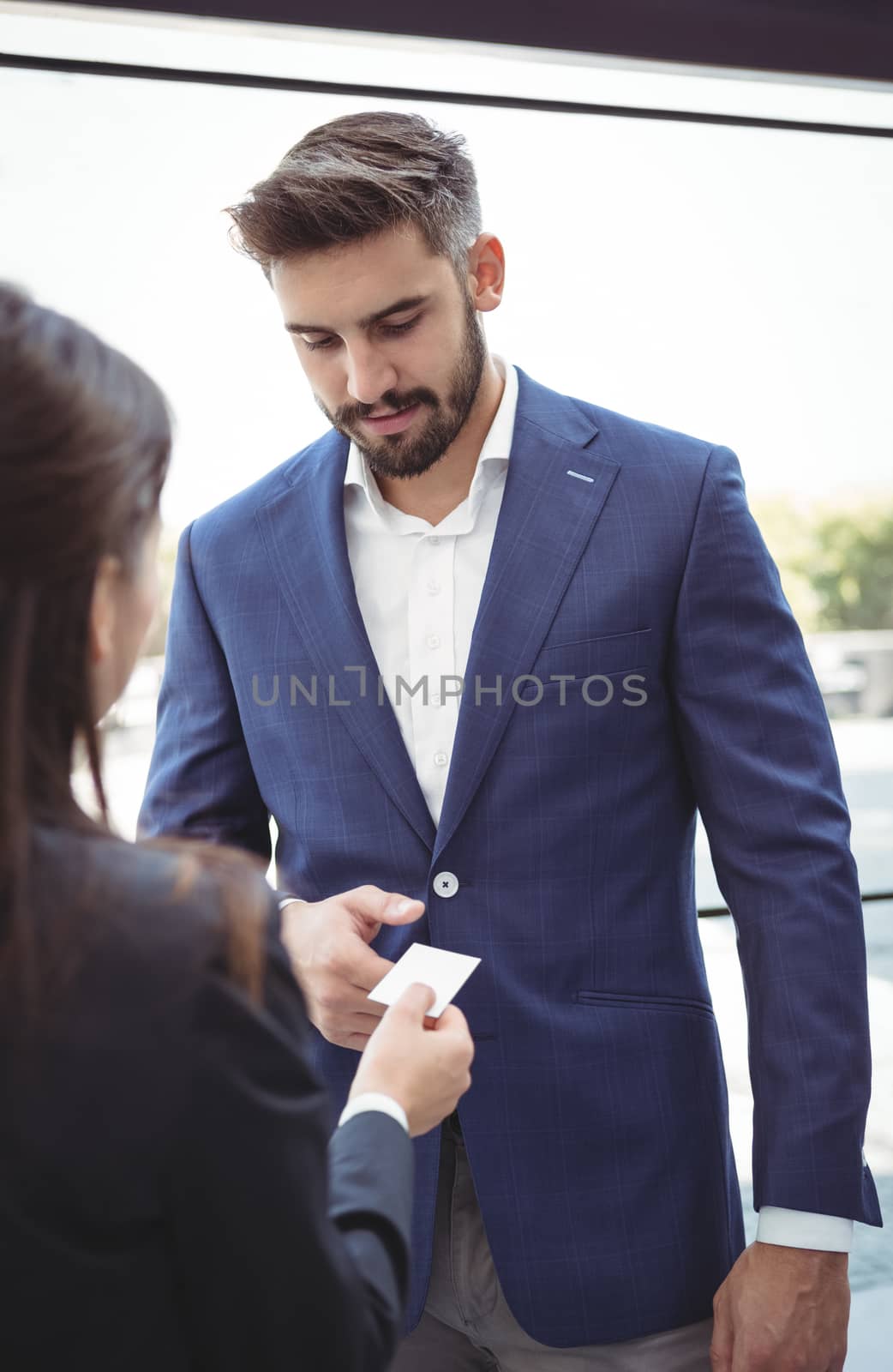 Businesswoman giving visiting card to businessman on platform