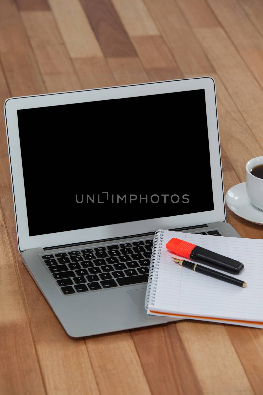 Cup of coffee with laptop, organizer, maker and pen on wooden background