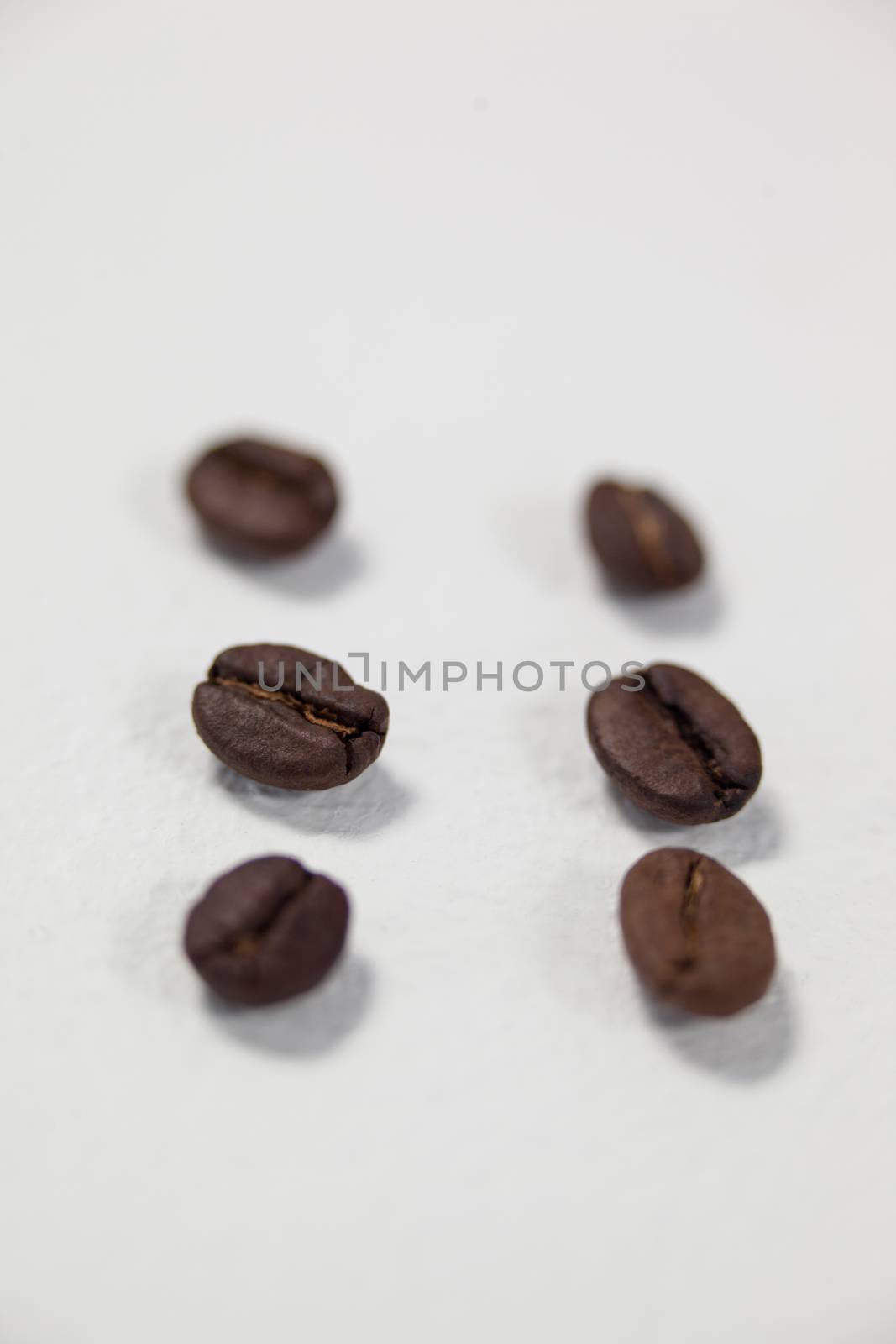 Roasted coffee beans arranged on white background