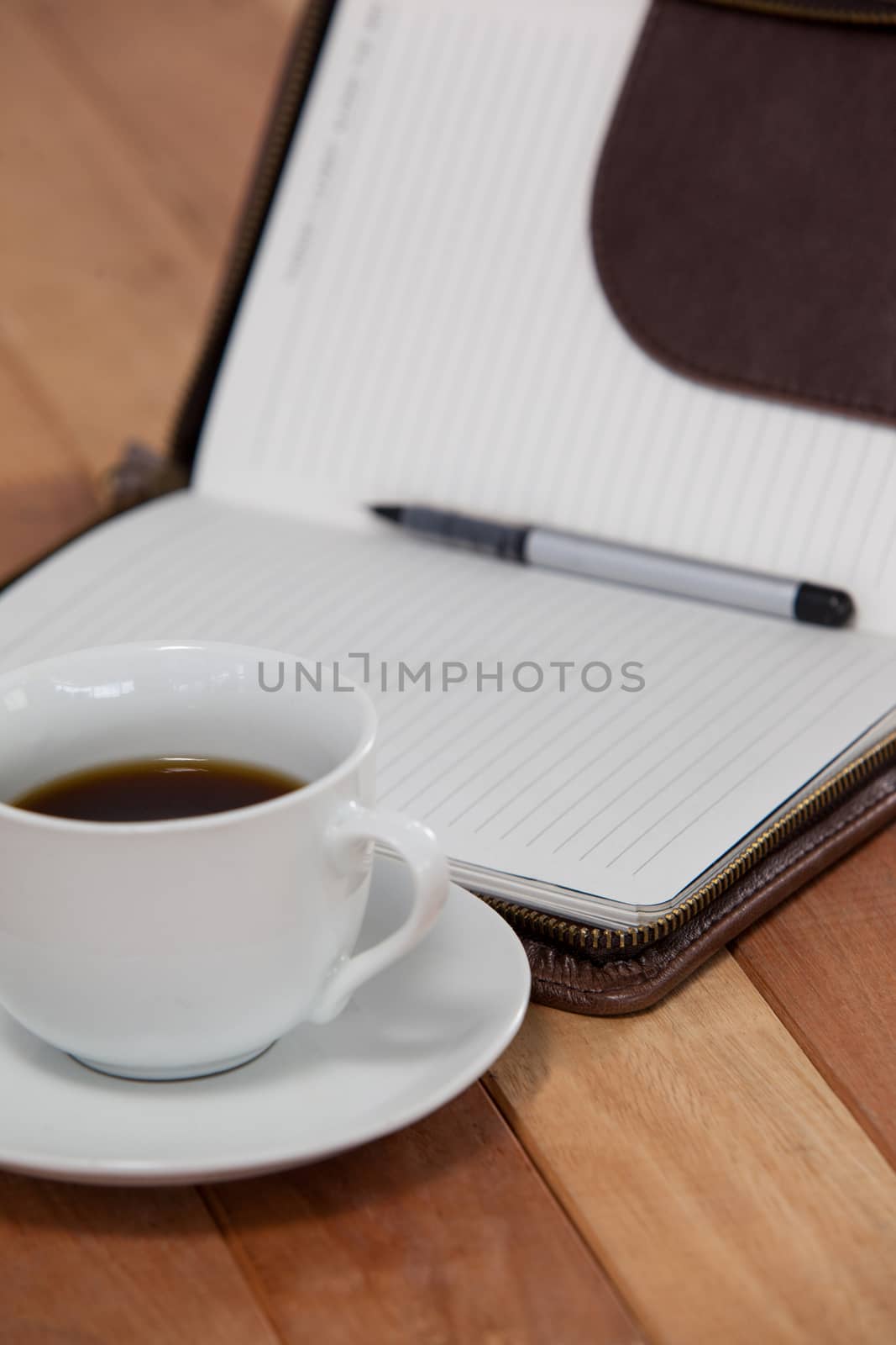 Black coffee with organizer and pen on wooden background