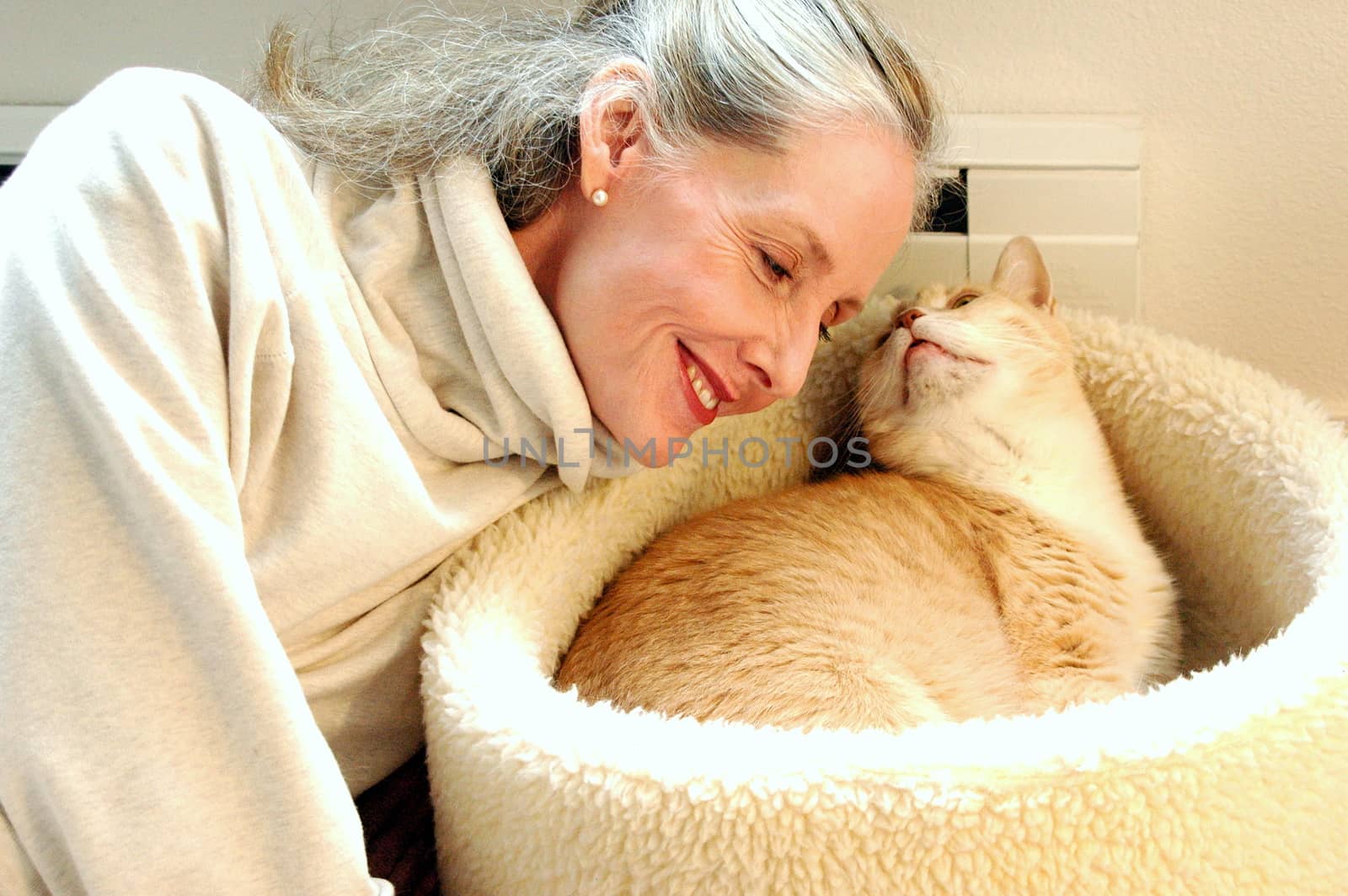 Mature female blond beauty bonding with her cat at home.
