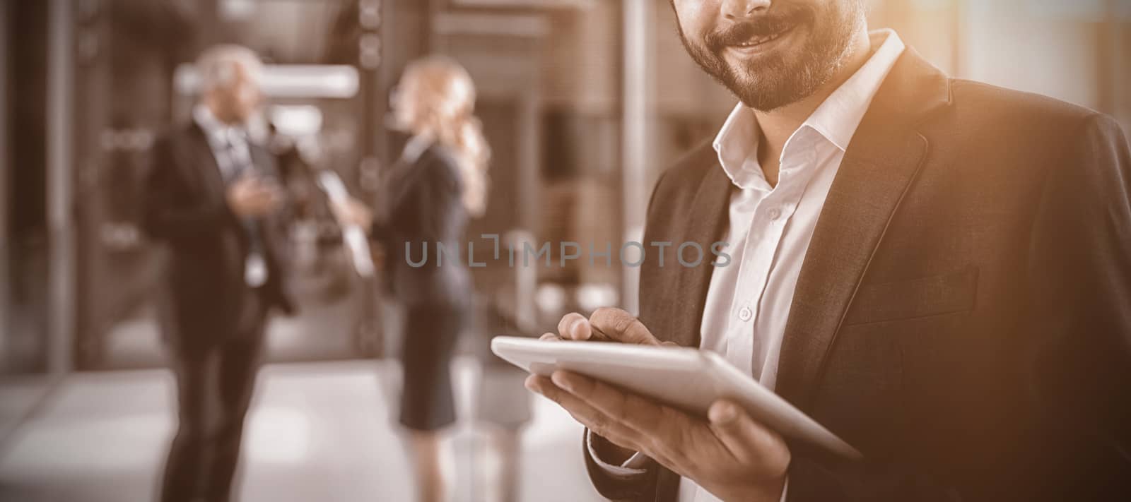 Portrait of businessman using digital tablet in office corridor