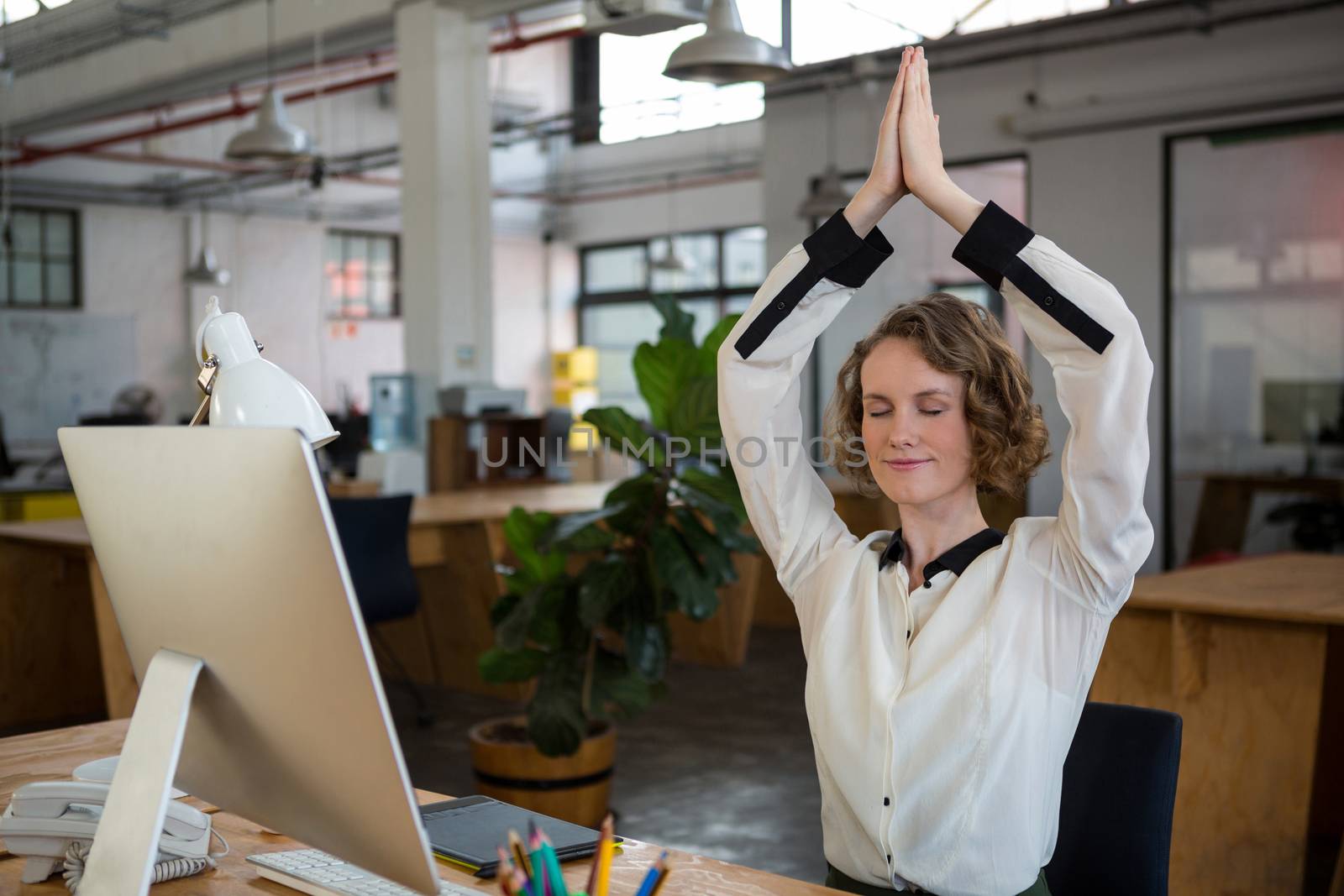 Female graphic designer performing yoga by Wavebreakmedia