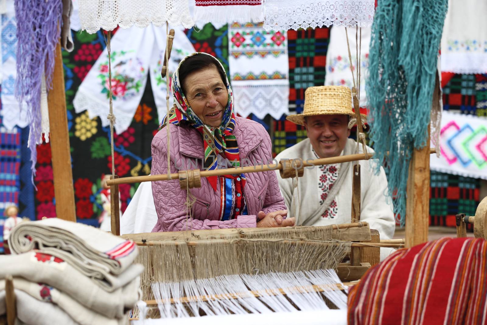 Grandmother works behind an old spinning machine.Spice on an old spinning wheel. Ancient fabrication. Woman weaver