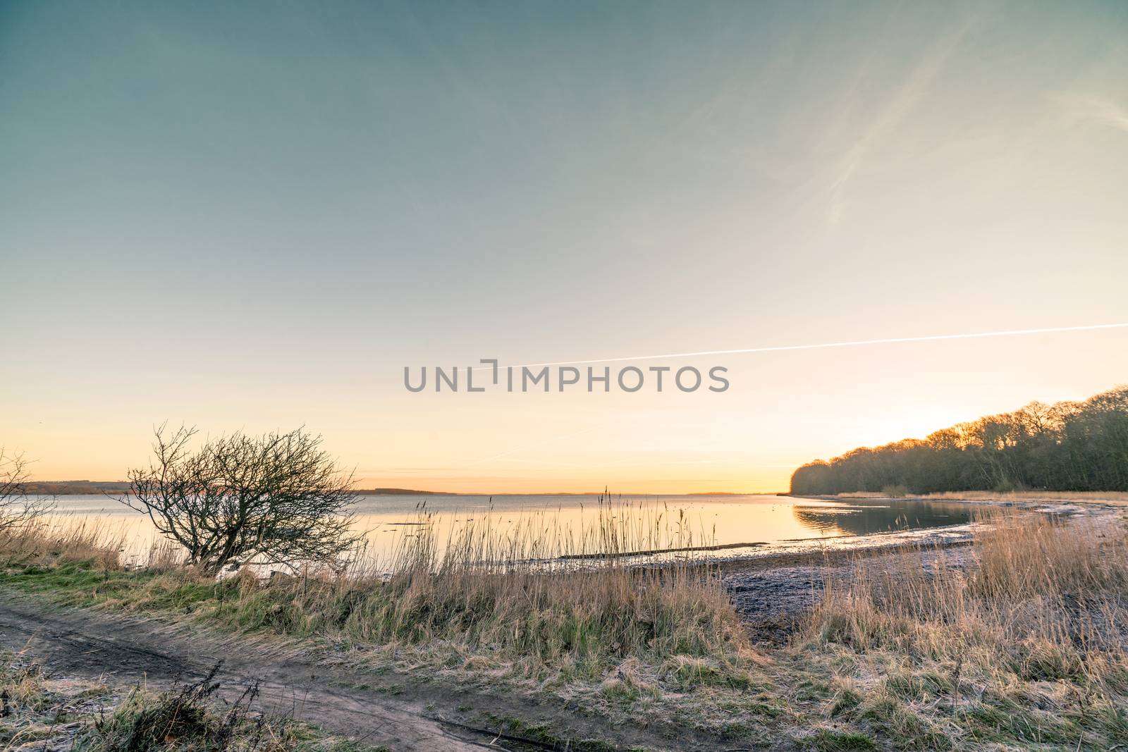 Sunrise over a lake in the winter with frost in the grass on a cold morning