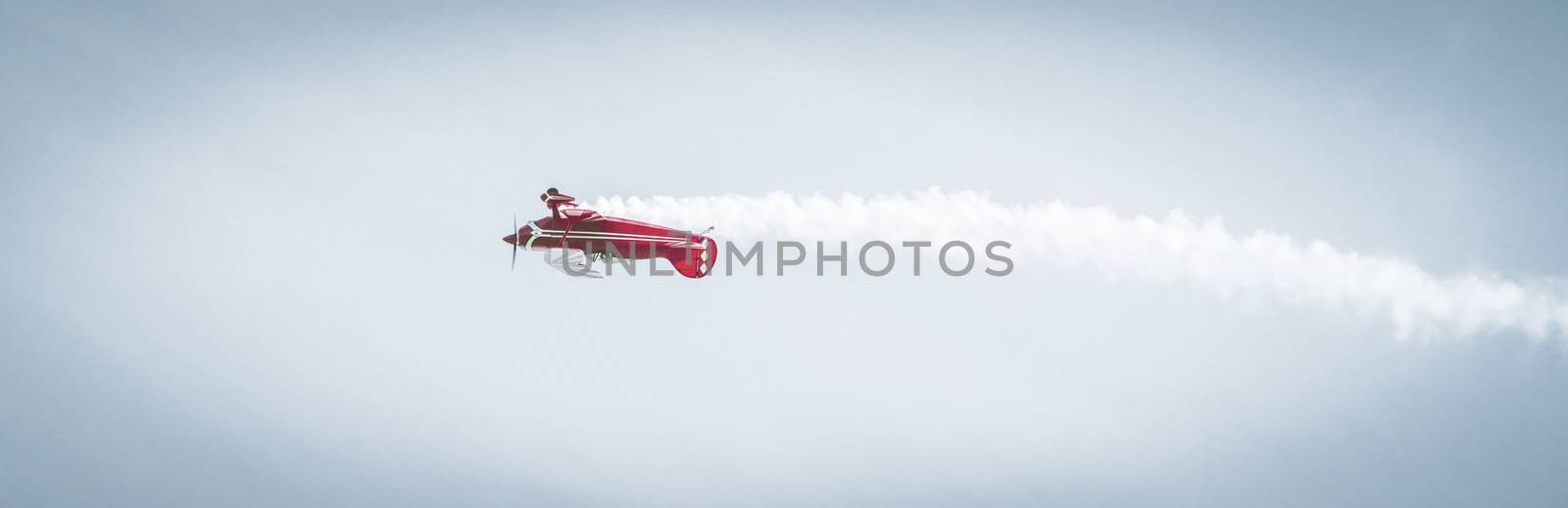 Red airplane flying loop with steam coming out by Sportactive