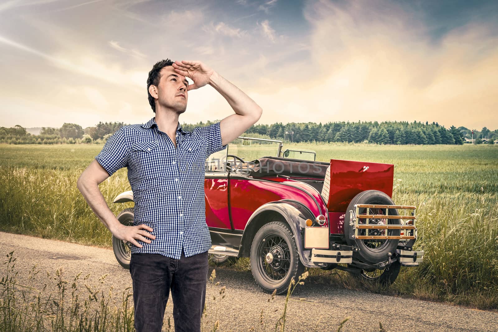 Car out of fuel in a rural countryside with a male in a blue shirt scouting for help